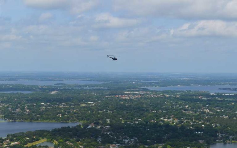 aerial over central florida with blue helicopter in cloudy sky for maxflight helicopter tours
