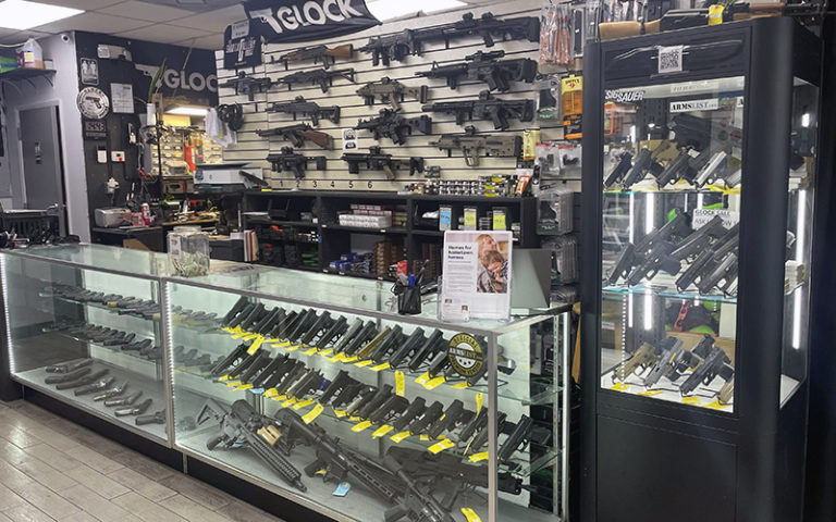 array of guns behind and inside display cases and counter at shooting gallery range orlando
