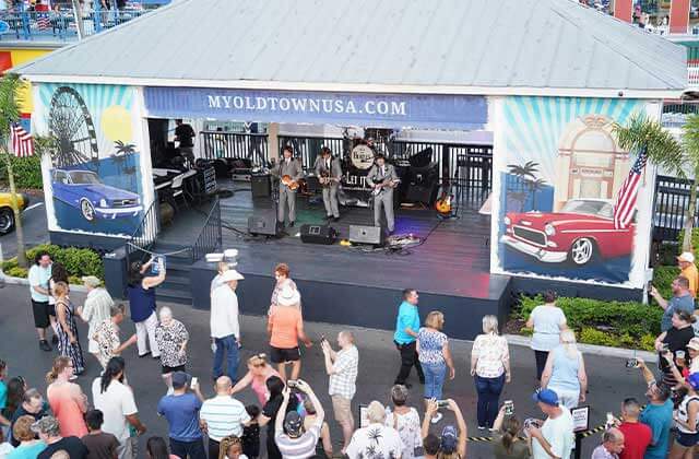 beatles impersonator band performing on stage with crowd dancing at old town entertainment district kissimmee