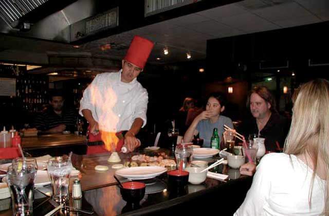 chef prepares food on hibachi table while diners watch oishi japanese restaurant orlando