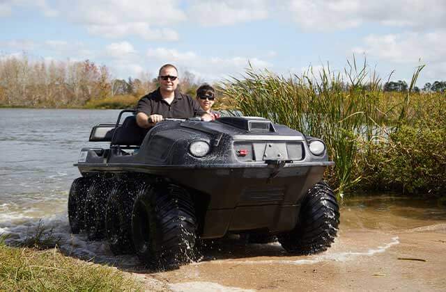 dad and son drive from the water up a bank in a mucky duck atv vehicle at revolution adventures clermont