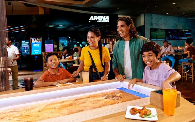 family of four playing shuffleboard in arcade area at dave busters orlando