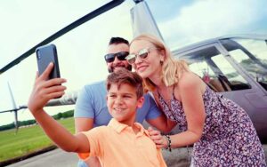family posing for selfie with helicopter on runway at maxflight helicopter services kissimmee