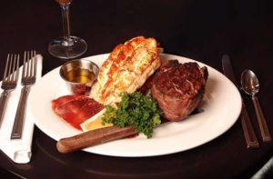 fine dining tabletop plate setting with lobster and filet mignon with a glass of wine at black angus steakhouse florida