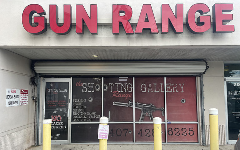 front exterior of gun range with roll down red signage machine gun graphics at shooting gallery range orlando