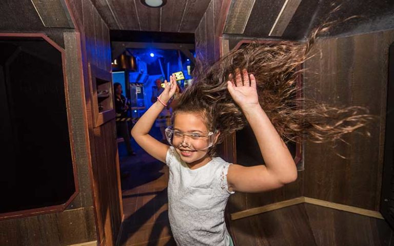 girl with long hair blowing around in storm simulator at wonderworks orlando