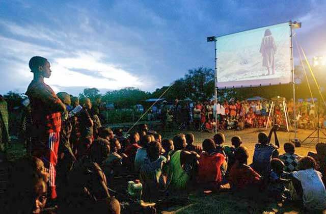 group of african villagers watch projector screen at jesus film project orlando