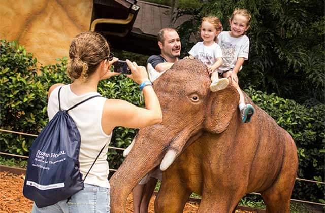 kids pose riding mammoth statue at dinosaur world
