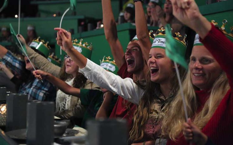 ladies seated dining and cheering while wearing green at medieval times dinner and tournament orlando