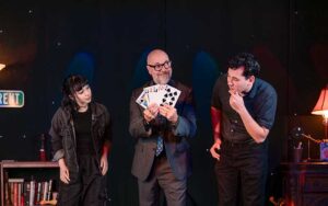 magician holding cards with volunteer couple at outta control magic comedy dinner show orlando