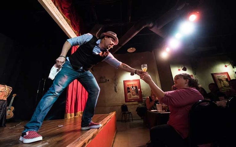 magician reaches for drink from audience member at outtacontrol magic comedy dinner show wonderworks orlando