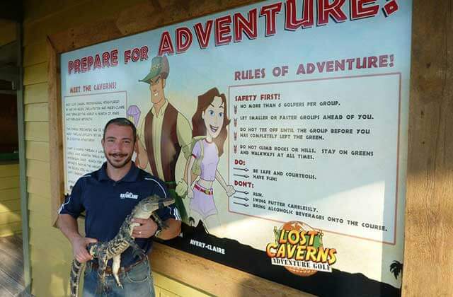 man holding small alligator with lost caverns sign lost caverns adventure golf orlando