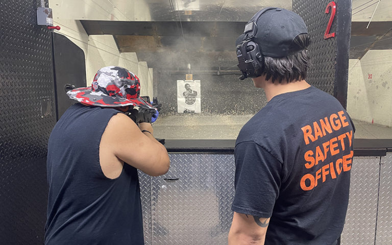 man shooting machine gun at target in range with safety officer at shooting gallery range orlando