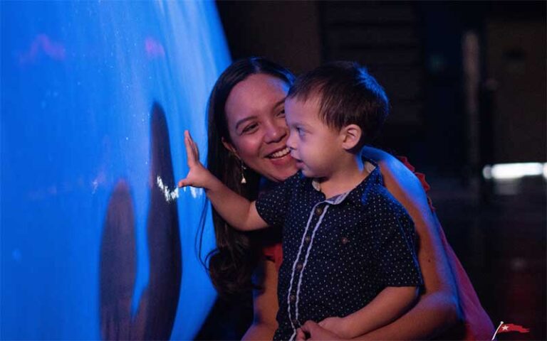 mom holding child interacting with map display at titanic the artifact exhibition orlando