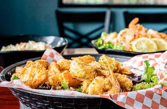 three black woven baskets with red and white checkered food paper holding fried shrimp with lemon and lettuce garnish and a bowl of coleslaw at nantucket shrimp shack restaurant in kissimmee florida