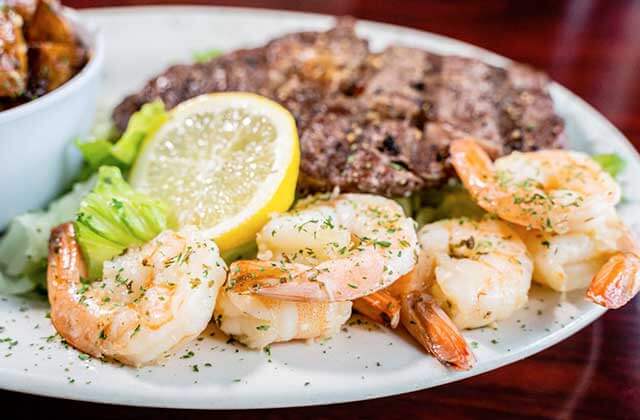 cooked shrimp next to a steak with lemon garnish and a bowl of potatoes at Nantucket Shrimp Shack in Kissimmee, Florida.