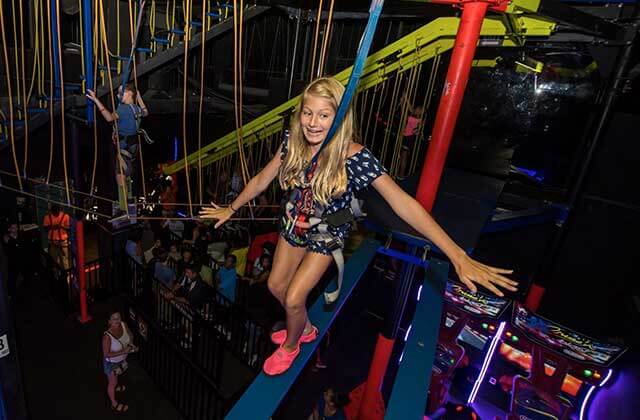 nervous girl balances on beam of ropes course at wonderworks orlando