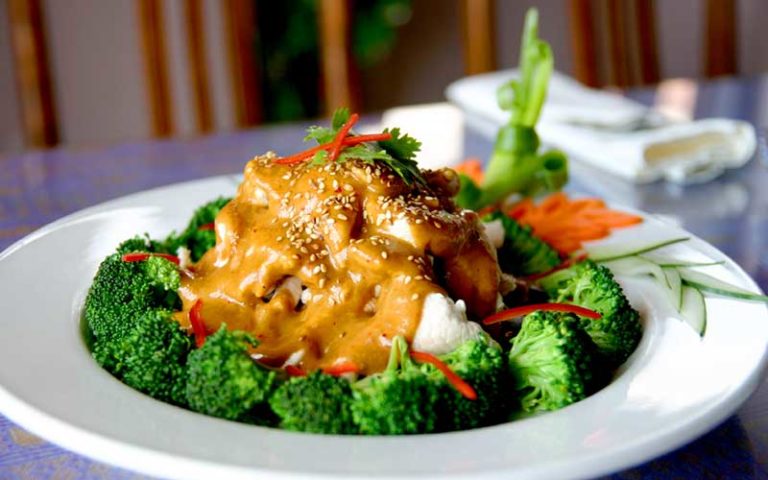 param steamed chicken entree with broccoli peanut sauce on white platter at thai thani