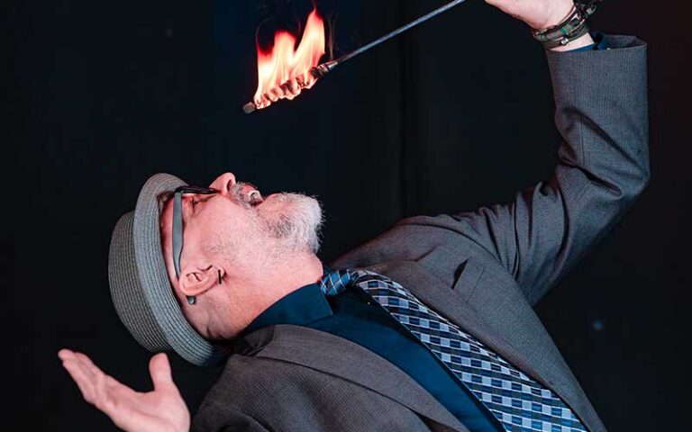 performer raising flaming torch to swallow at outta control magic comedy dinner show orlando
