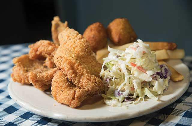plate of fried catfish hushpuppies slaw and fries at the catfish place kissimmee
