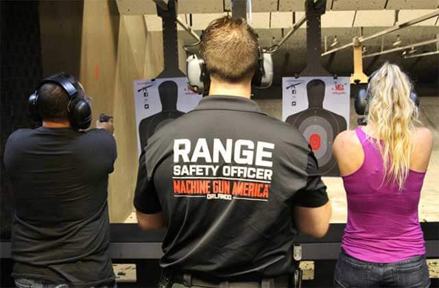 range safety officer stands between two shooters in a range at machine gun america kissimmee