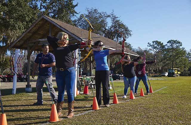 row of archers aim bows and arrows with trainer at revolution adventures clermont
