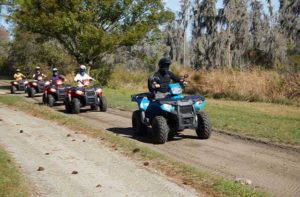 row of atvs drive along a path through trees at revolution adventures clermont
