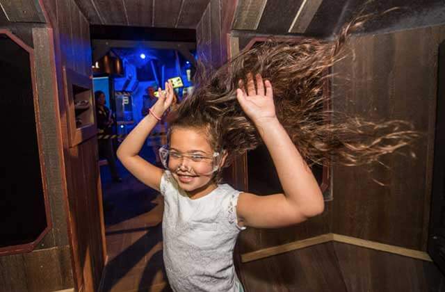 smiling girl with hair blowing wildly in wind tunnel wonderworks orlando