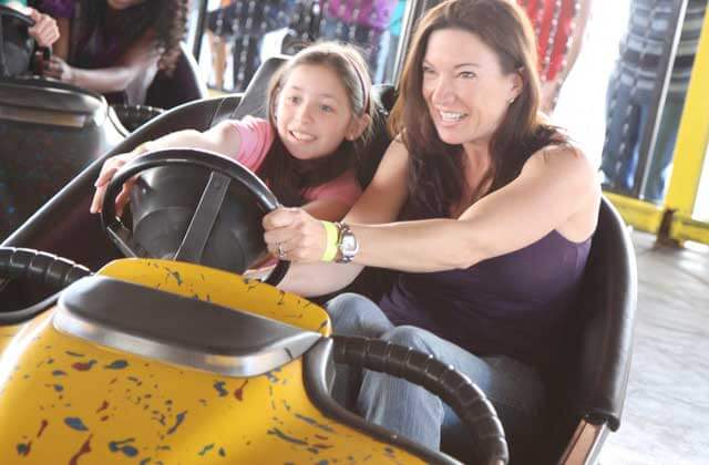 smiling mother daughter driving bumper car magical midway orlando