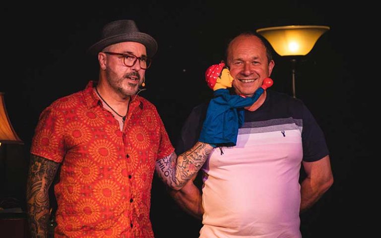 stage performer with hand puppet and laughing volunteer on stage at outta control magic comedy dinner show wonderworks orlando