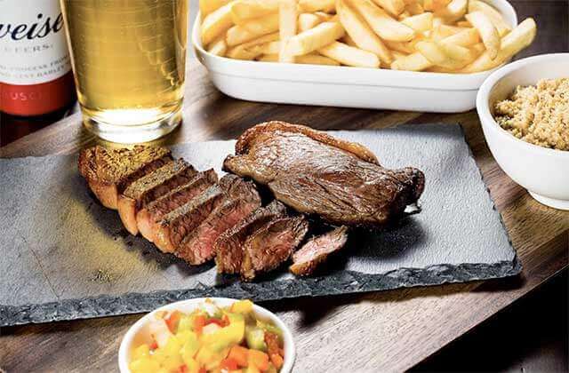 steaks cut and displayed with beer french fries and other sides at black fire brazilian steakhouse orlando