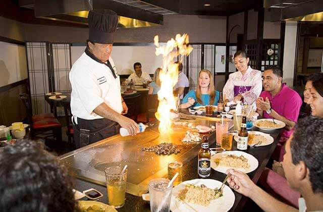 teppanyaki chef prepares food with a big flame with diners watching at shogun japanese steakhouse sakura sushi orlando