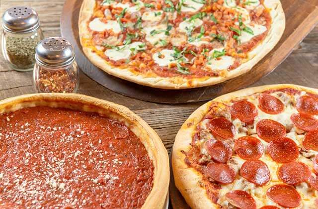 three different types of pizza with seasoning shakers at giordanos orlando kissimmee