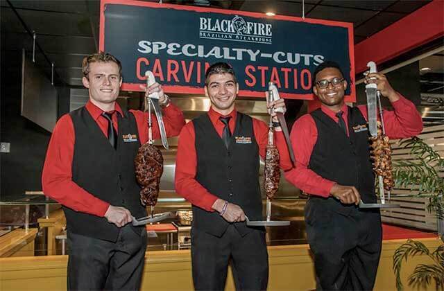 three male servers with skewers of meats at carving station at black fire brazilian steakhouse orlando