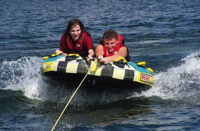 two boys hanging on to an inner tube towed across water at buena vista watersports orlando