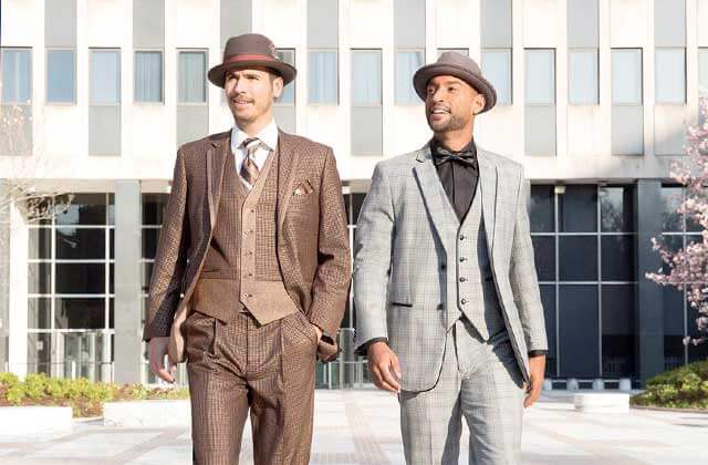 two young men wearing fashionable suits walking through a city plaza at orlandos gk menswear store