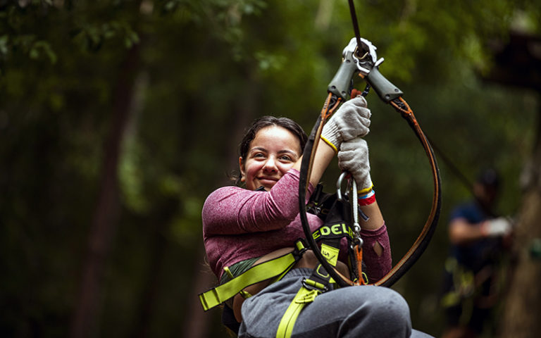woman seated in climbing gear with zip line cables at orlando tree trek