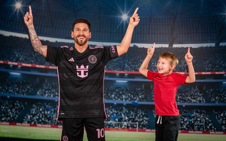 young fan cheers next to messi wax figure at madame tussauds orlando
