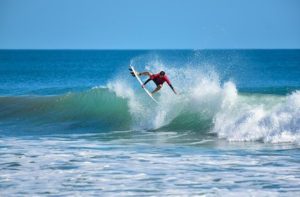 surfer in red gripping surfboard while flipping over crashing wave near the beach for the space coast destination feature