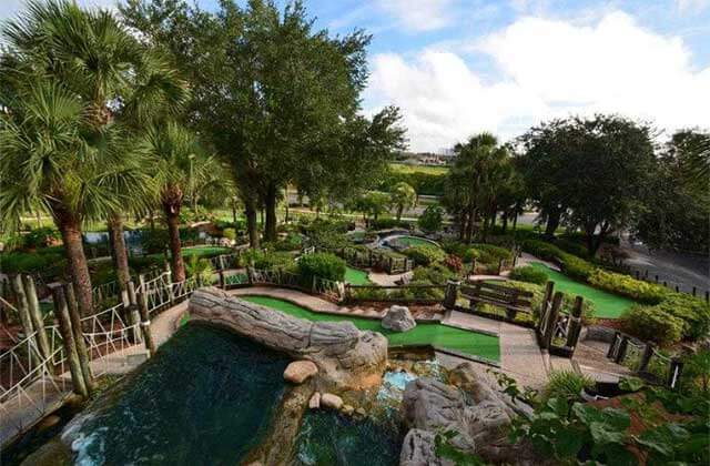 aerial view of mini golf greens with palm trees and running water at pirates cove adventure golf orlando