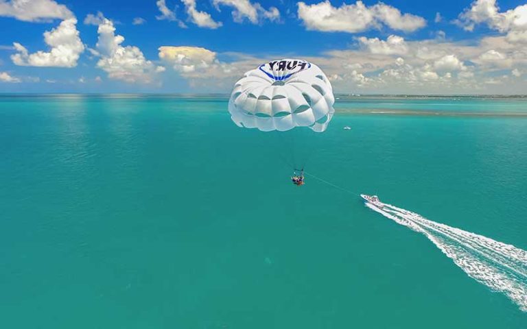 aerial view of speed boat pulling parasailer over turquoise water and blue cloudy sky at fury water adventures key west