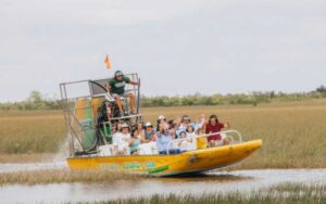 airboat with tour group speeding along wetlands at everglades alligator farm homestead