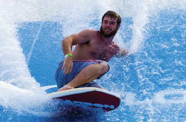 bearded man surfs on wave simulator at big kahunas water adventure park destin