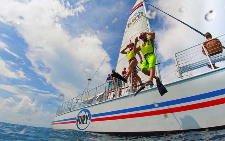 couple of snorkelers jump into the water from a sailing catamaran at fury water adventures key west