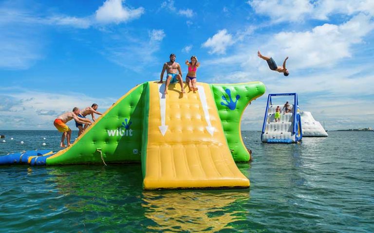 couple slide down floating obstacle slide while others climb up or jump off at fury water adventures key west