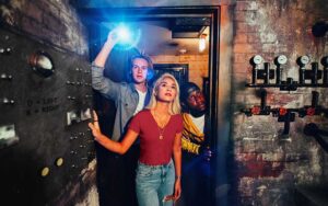 couple with flashlight look through basement area at the escape room orlando
