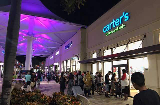 crowded shopping center outside corridor with stores and purple lighting at palm beach outlets west palm beach