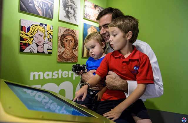 dad and sons play a game on a screen exhibit at miami childrens museum florida