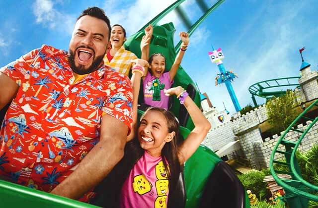 family of four screams while riding a roller coaster with dragon and castle theme at legoland florida resort