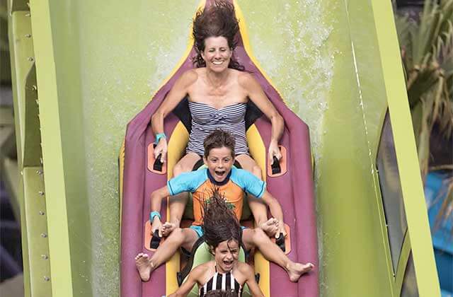 family of three riding down flume on raft at universals volcano bay water park orlando